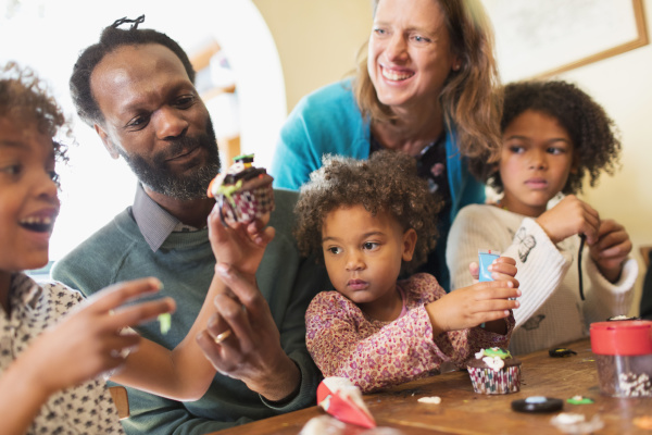feliz familia multietnica decorando cupcakes en
