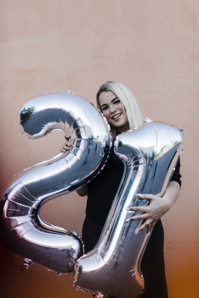 joven sonriente sosteniendo globos numero 21